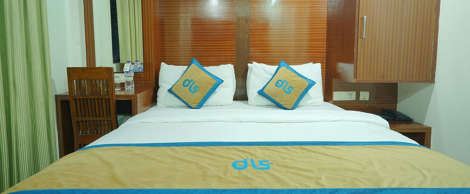 Deluxe room with a king size bed, adorned with a stylish wooden headboard at DLS Hotels The Rock Castle.